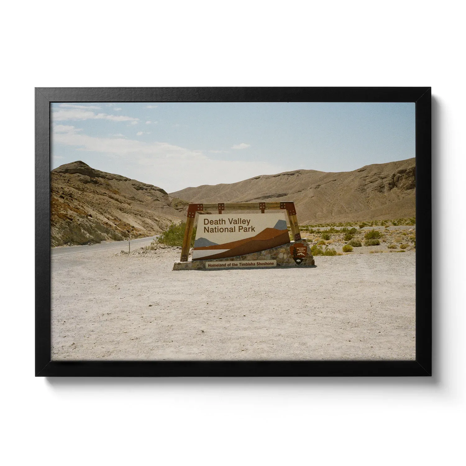 Picture of a gravel parking lot, with the entrance sign to Death Valley National Park