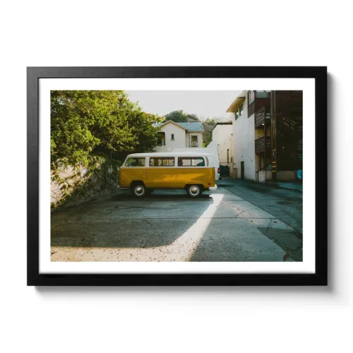 Alter gelber VW Buli der in einer Seitenstraße parkt, dazu cooler Lichteinfall (Vintage Look)