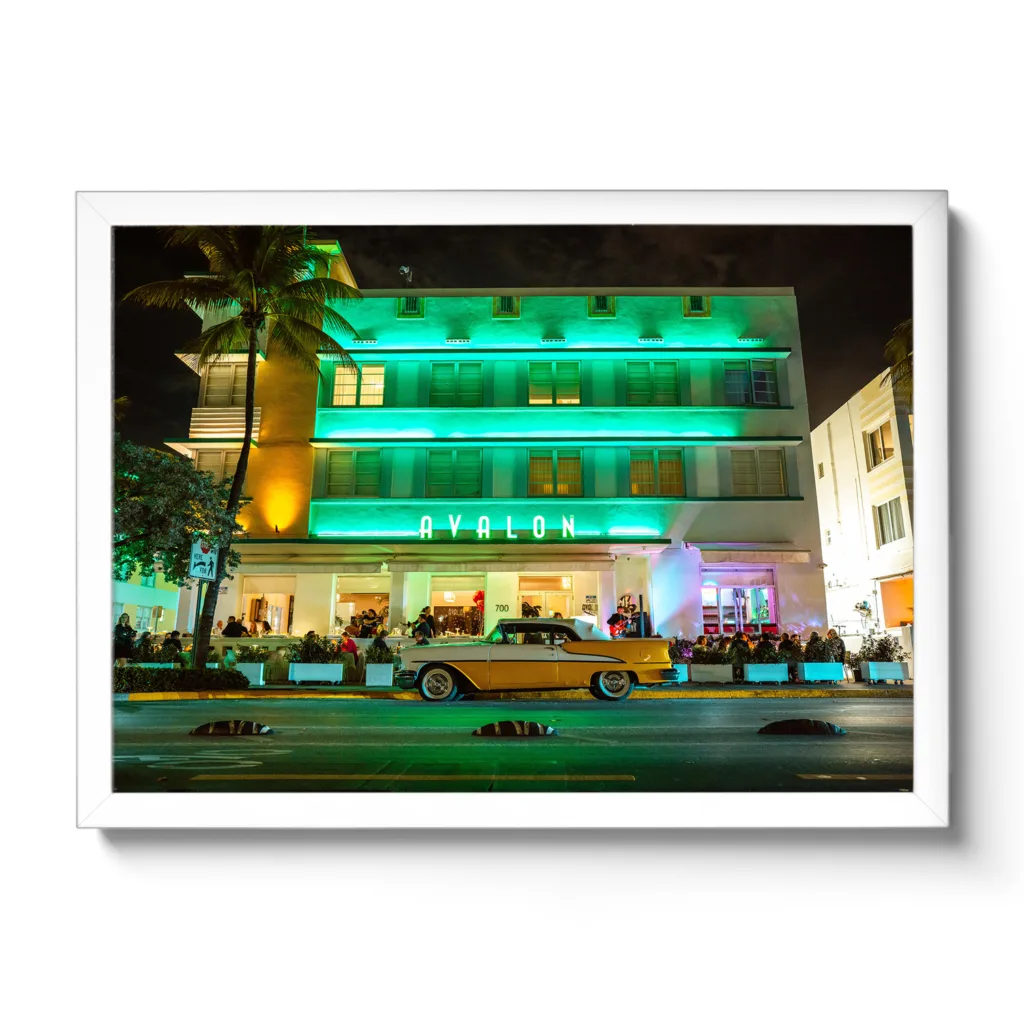 Landscapeaufnahme vom Avalon Hotel Miami am Ocean Drive mit einem gelben Oldtimer davor.
