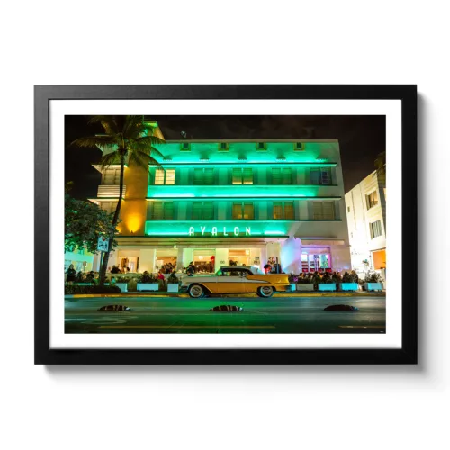 Landscape shot of the Avalon Hotel Miami on Ocean Drive with a yellow vintage car in front of it.