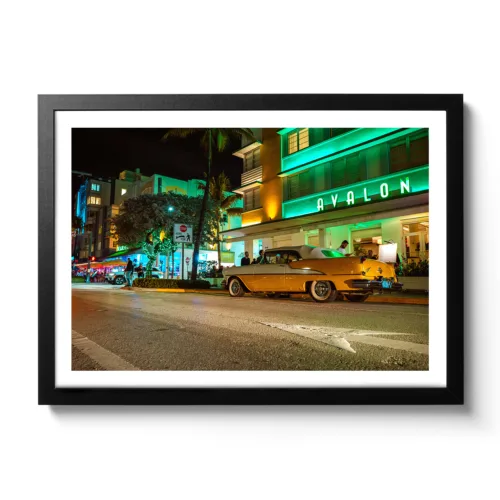 Bildaufnahme vom Avalon Hotel Miami am Ocean Drive mit einem gelben Oldtimer davor.