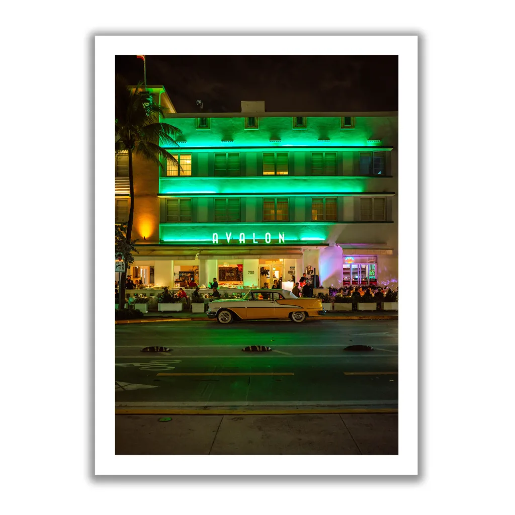 Bildaufnahme im Hochformat vom Avalon Hotel Miami am Ocean Drive mit einem gelben Oldtimer davor.