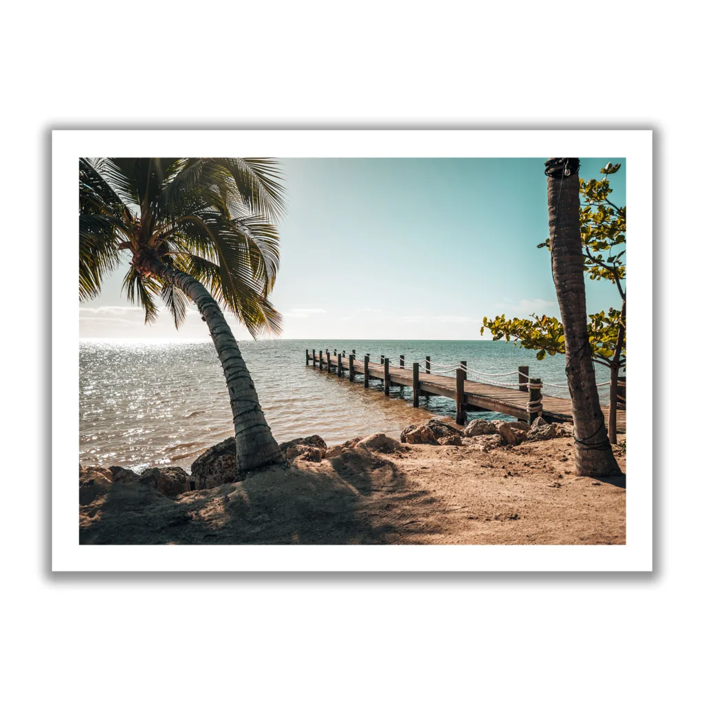 Bildaufnahme eines Steges der ins Meer hinausgeht und links und rechts befinden sich Palmen. Vormittagsstimmung mit Sonne und Meer.