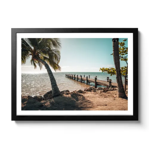 Bildaufnahme eines Steges der ins Meer hinausgeht und links und rechts befinden sich Palmen. Vormittagsstimmung mit Sonne und Meer.