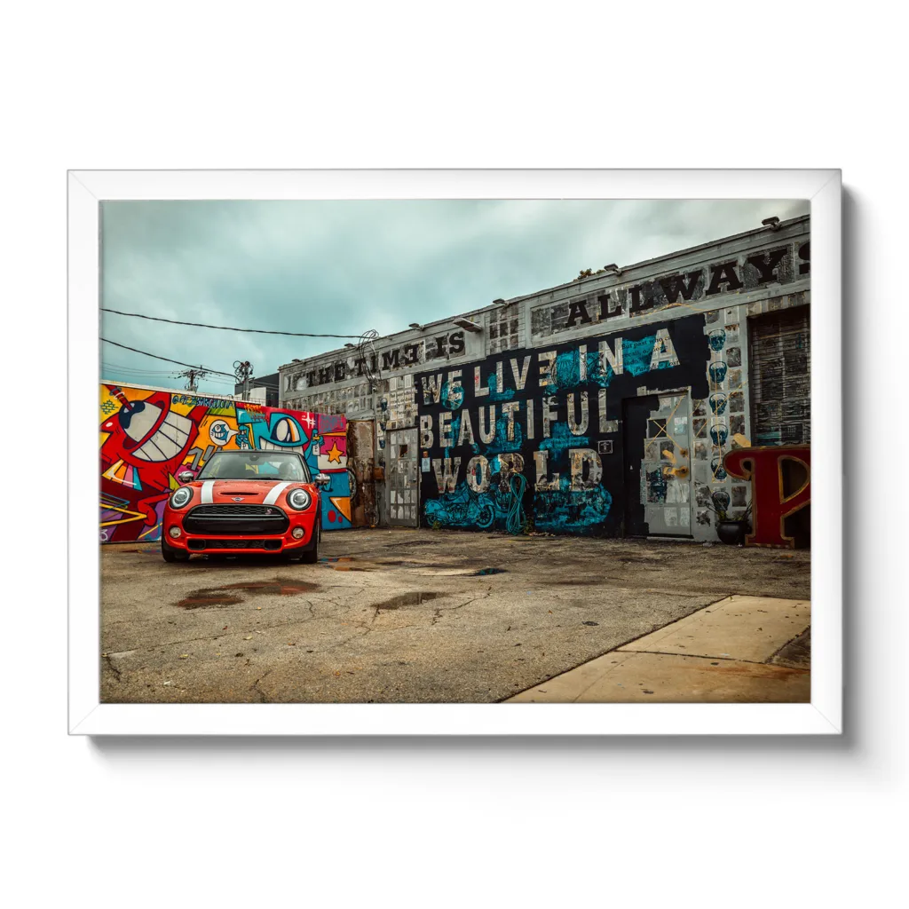 Bildaufnahme von einer Autowerkstatt, die mit Graffiti bemalt ist und ein roter Mini davor parkt.
