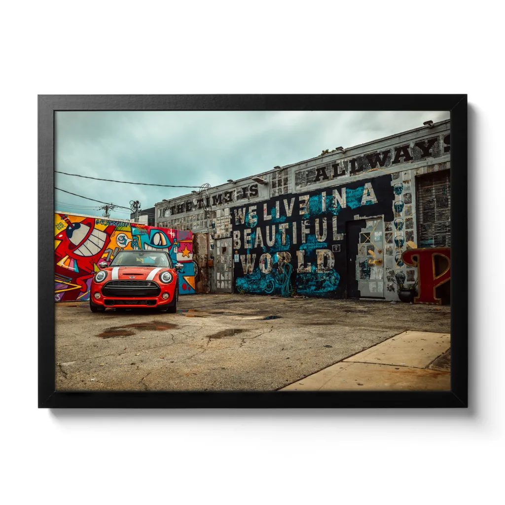 Bildaufnahme von einer Autowerkstatt, die mit Graffiti bemalt ist und ein roter Mini davor parkt.