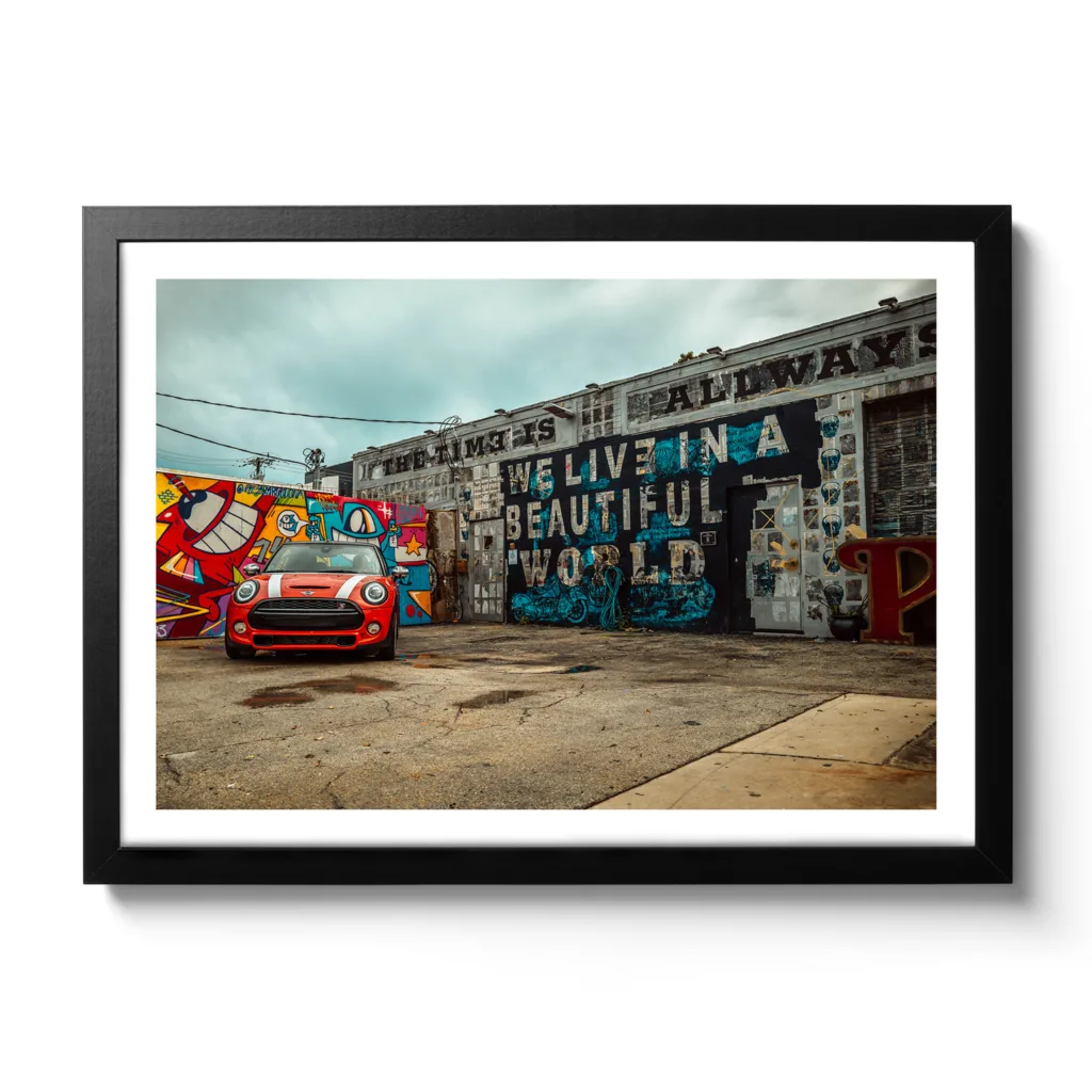 Bildaufnahme von einer Autowerkstatt, die mit Graffiti bemalt ist und ein roter Mini davor parkt.