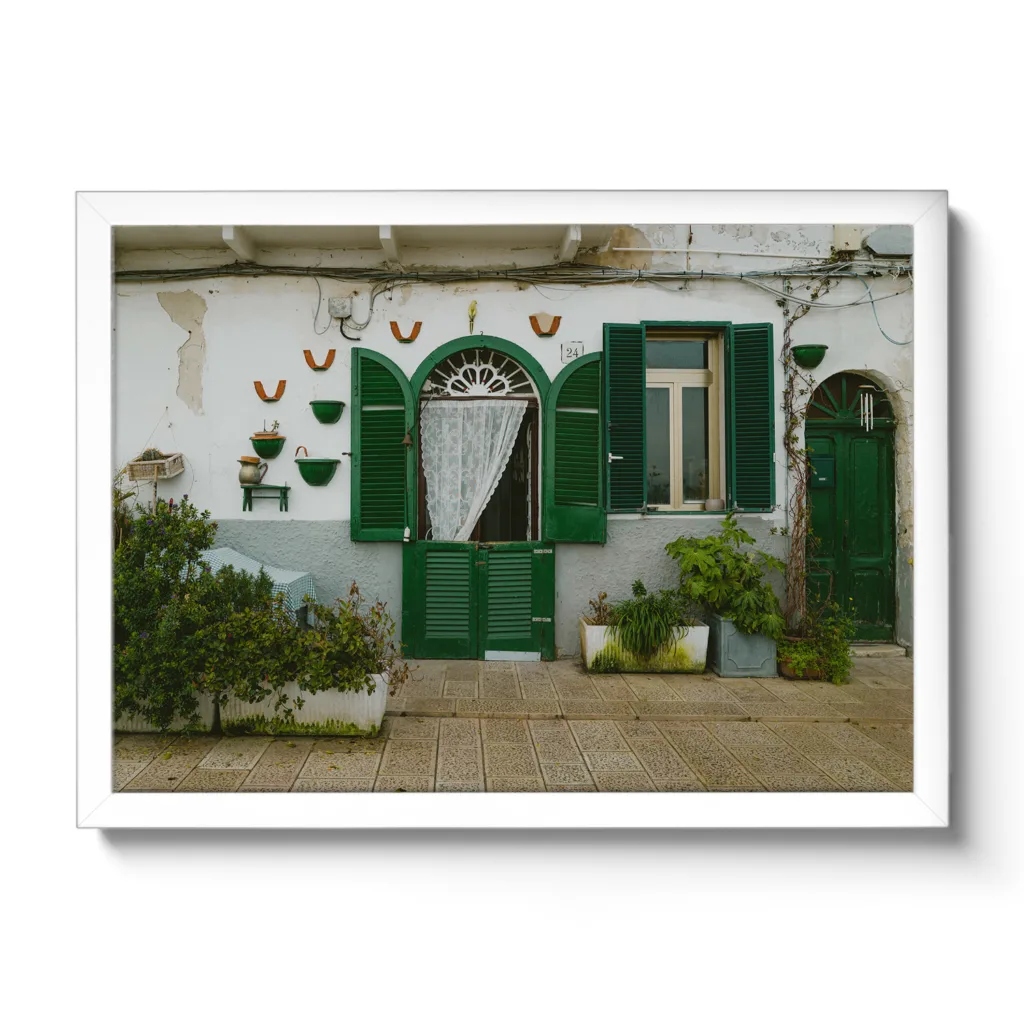 Bildaufnahme einer kleinen italienischen Hausmauer mit grünen Fensterläden.