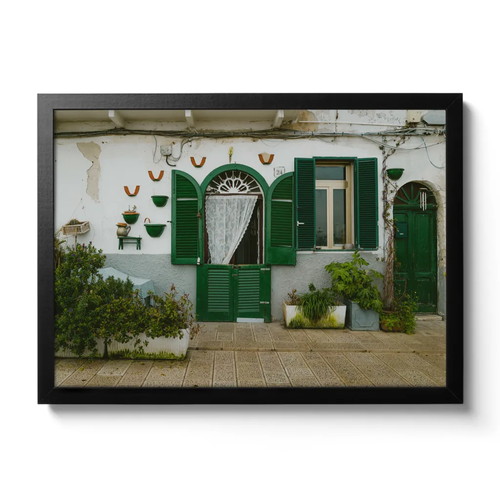 Bildaufnahme einer kleinen italienischen Hausmauer mit grünen Fensterläden.