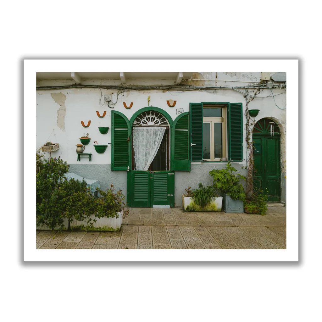 Bildaufnahme einer kleinen italienischen Hausmauer mit grünen Fensterläden.