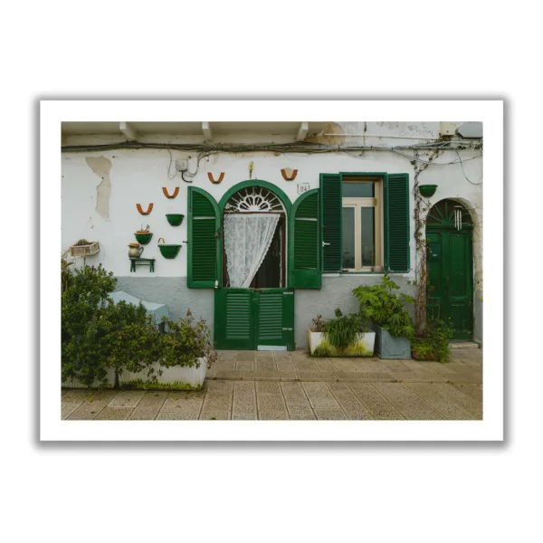 Bildaufnahme einer kleinen italienischen Hausmauer mit grünen Fensterläden.