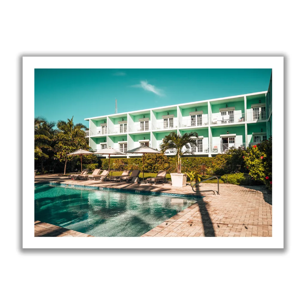 Bildaufnahme des Pool-Bereiches des Grassy Flat Hotel. Blauer Himmel, Pool und Liegen. Morgenansicht.
