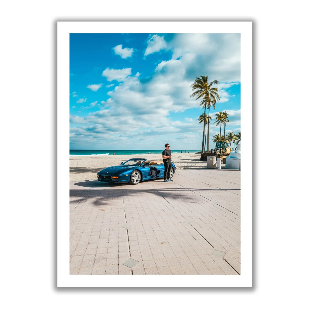 Junger Mann steht vor einem blauen Ferrari am Strand von Fort Lauderdale.