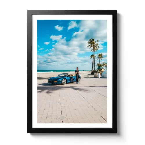 Junger Mann steht vor einem blauen Ferrari am Strand von Fort Lauderdale.