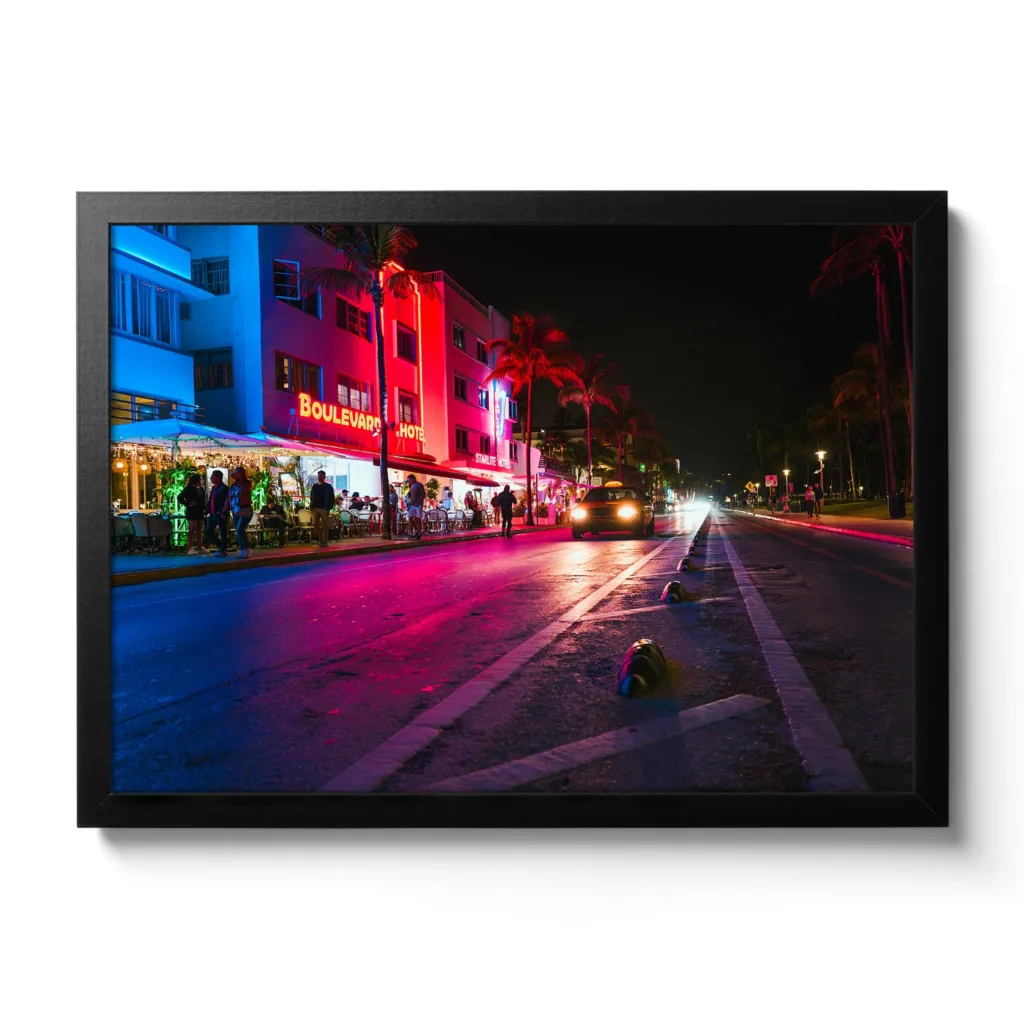 Bildaufnahme vom Ocean Drive in Miami bei Nacht. Neonlichter und ein fahrendes Auto.