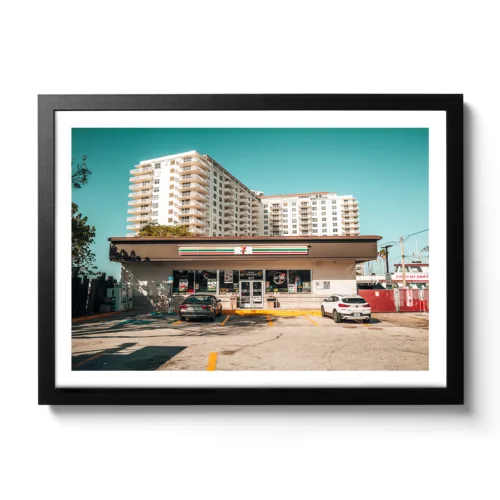 Landscape shot of a Seven Eleven supermarket with parking lot in Fort Lauderdale. Behind it a white hotel.