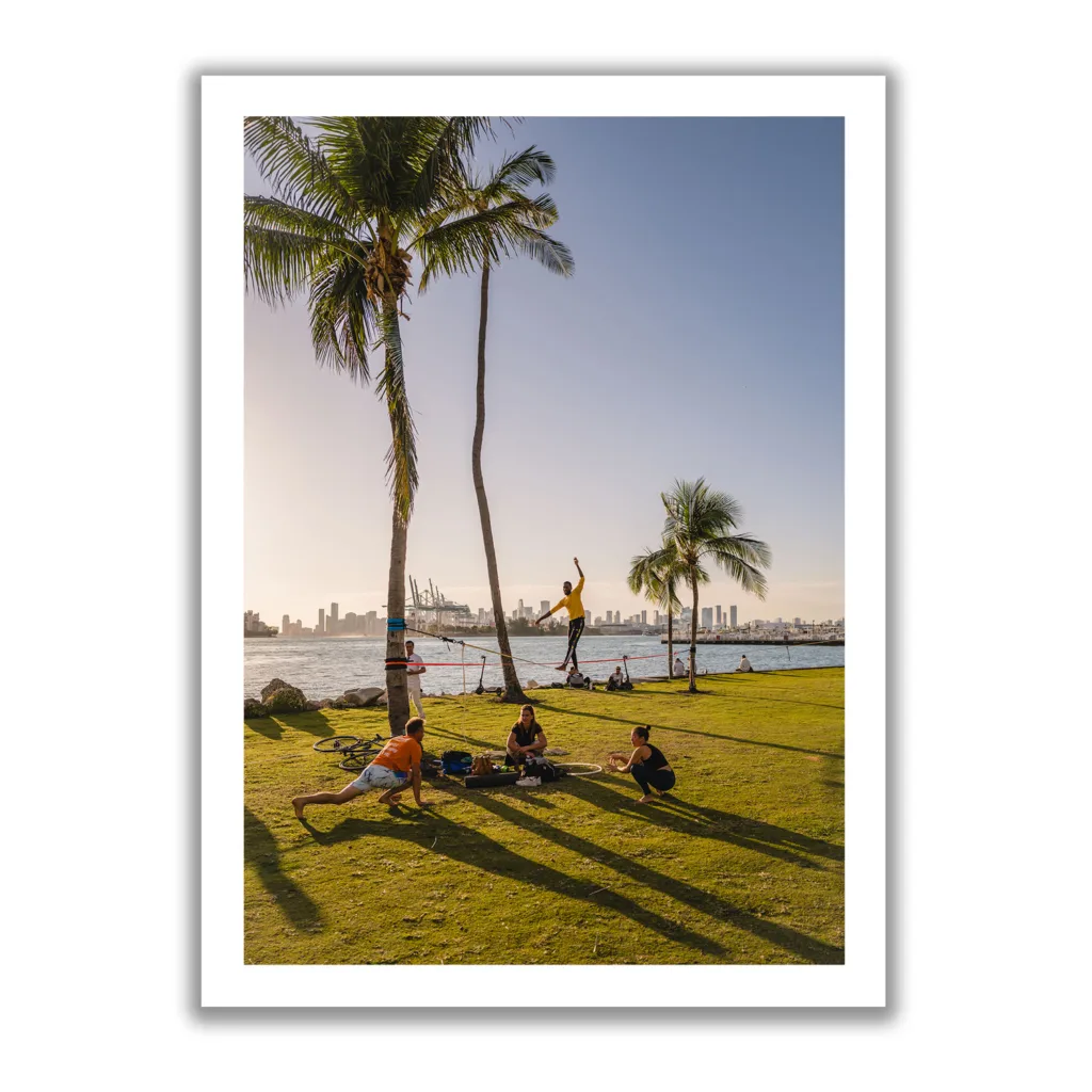 Bildaufnahme vom South Pointe Miami, wo ein Mann auf einer Slackline steht und davor eine Yoga-Gruppe.